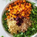 Salad bowl with arugula, roasted butternut squash, quinoa, pecans, and dried cranberries