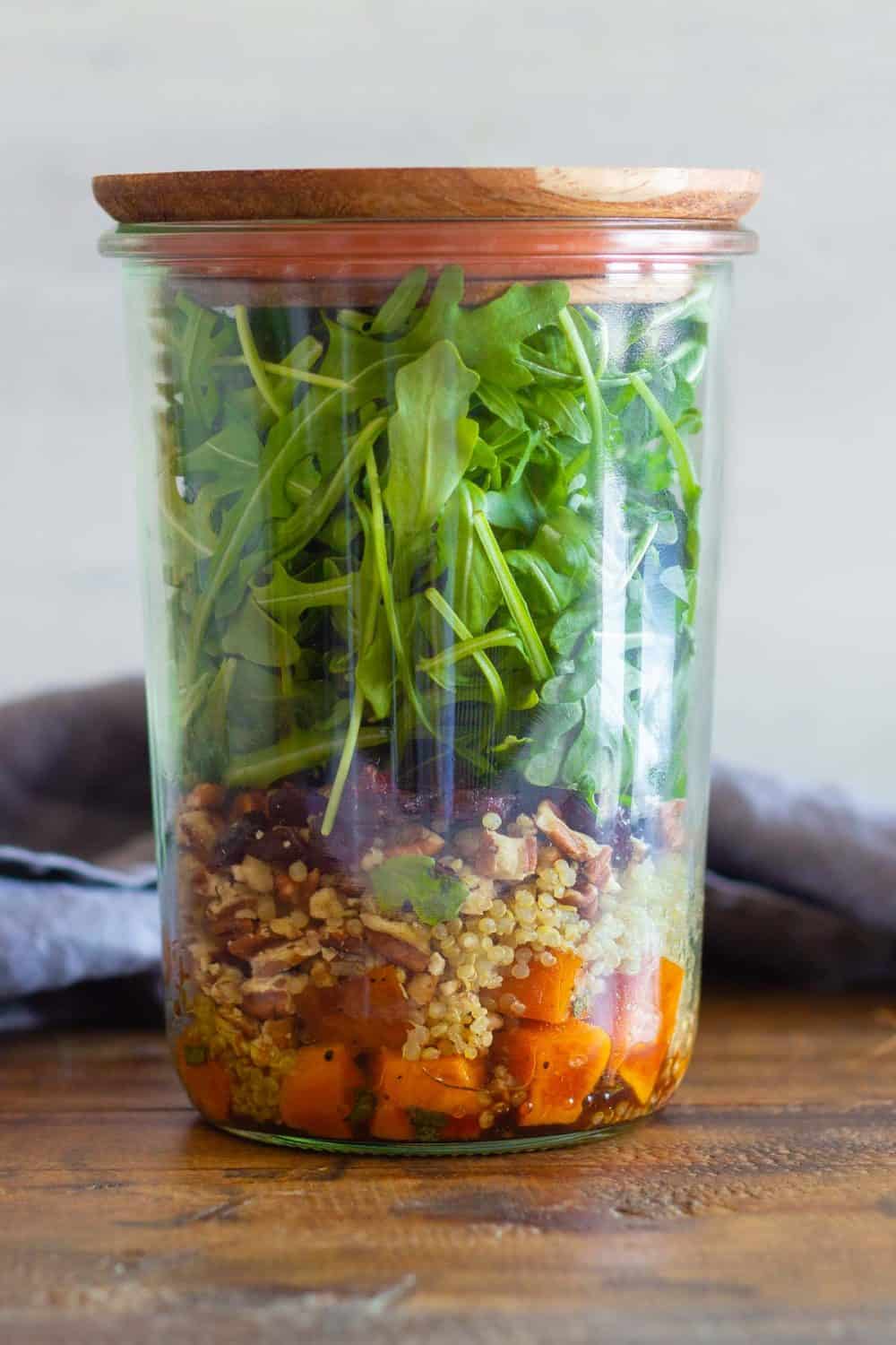 Butternut squash salad in a tall glass jar with wooden lid