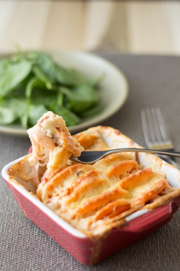 Sweet Potato Leek Salmon Gratin in a red baking dish and a close up of a fork showing a bite.