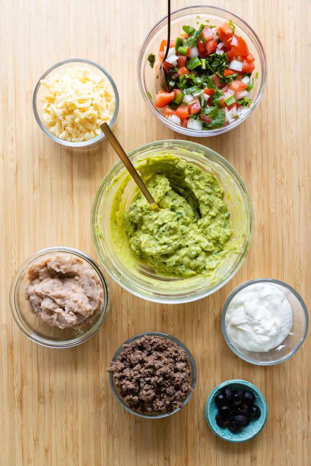 Ingredients for a sophisticated 7-Layer Dip laid out on a kitchen counter.