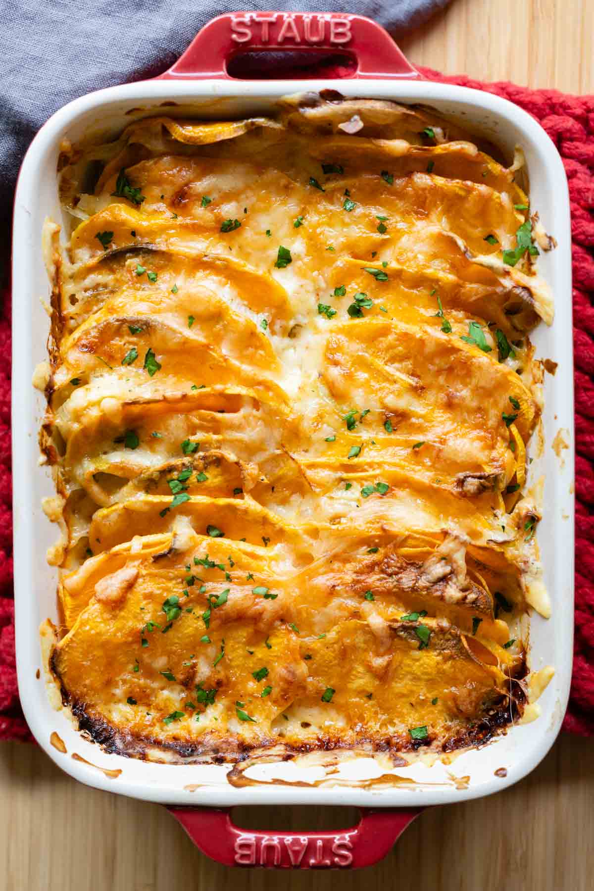 Red casserole dish with sweet potato gratin in it.