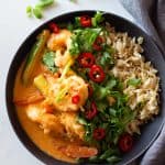 Coconut Shrimp Curry and brown rice in a grey bowl topped with herbs and chili.