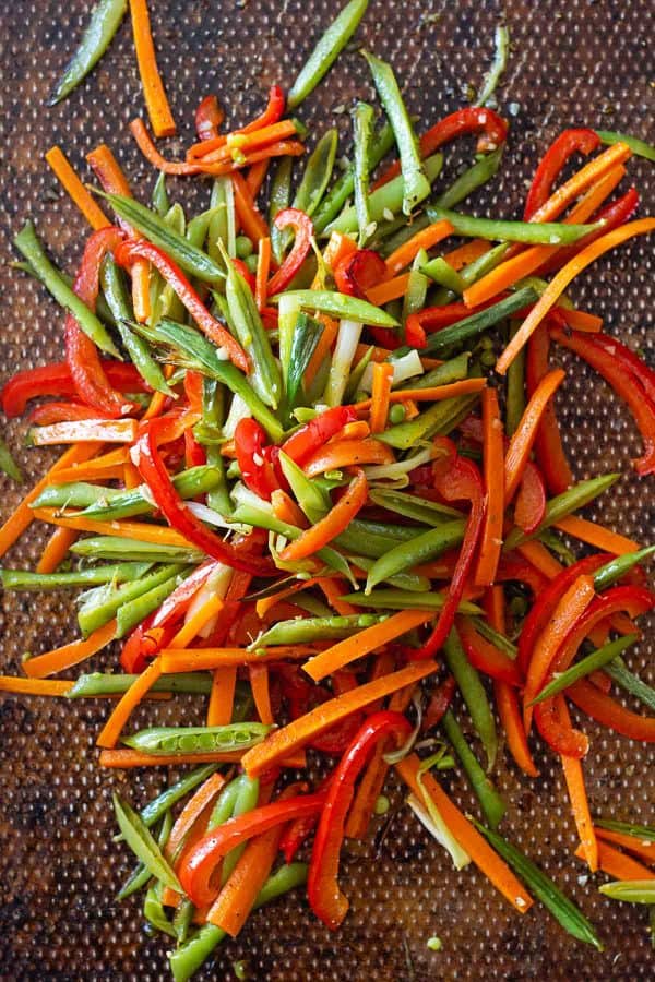 Sliced vegetables stacked on a baking sheet.