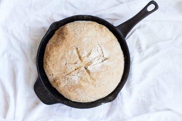 Freshly baked No-Knead Sesame Seed Bread in a black skillet on a white towel.