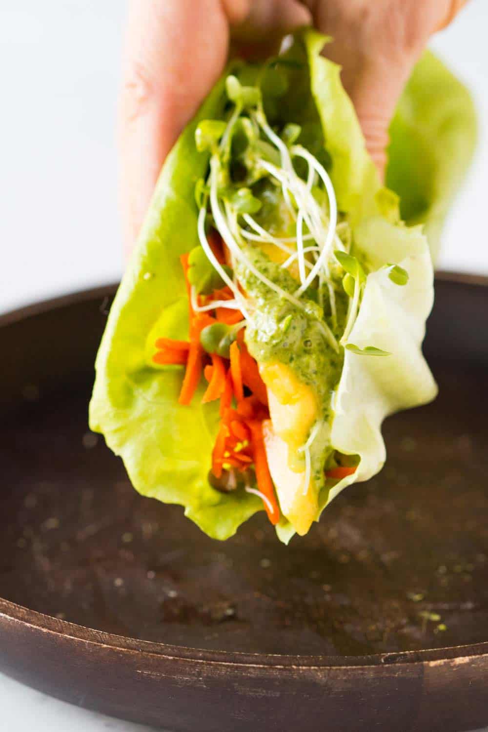 Close up of lettuce wrap with green sauce.