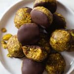 Pistachio Cookies dipped in chocolate piled on a small plate.