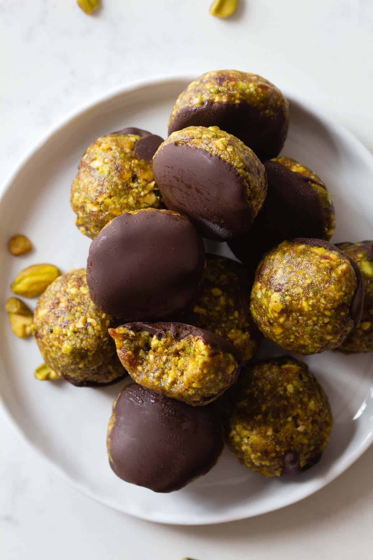Pistachio Cookies dipped in chocolate piled on a small plate.