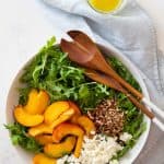 sliced nectarine, crumbled feta, chopped pecan on arugula in salad bowl