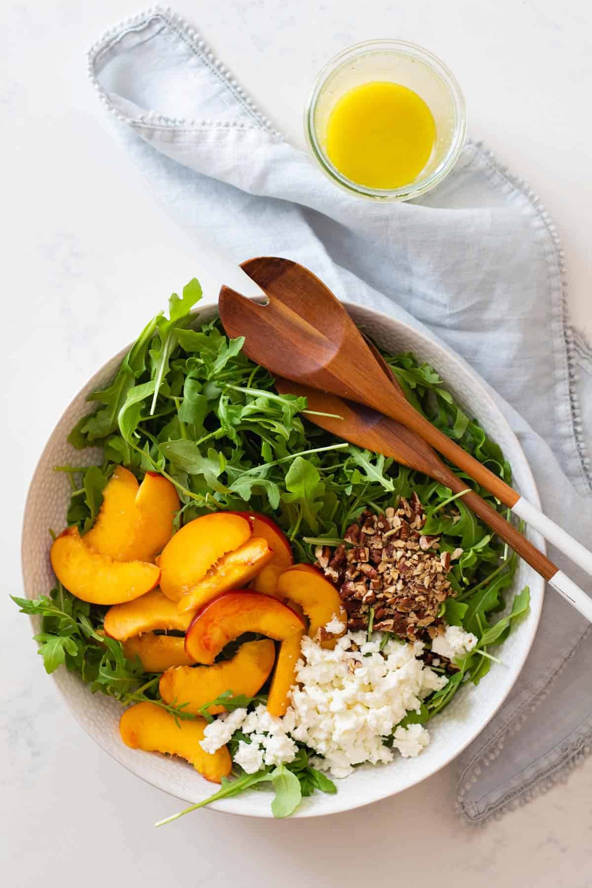 sliced nectarine, crumbled feta, chopped pecan on arugula in salad bowl