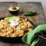 Butternut Squash Nachos in a black skillet with a green napkin on a wooden board.