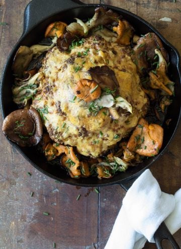 Top view of Whole Roasted Cauliflower with Wild Mushrooms in a skillet.