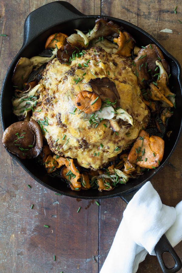 Top view of Whole Roasted Cauliflower with Wild Mushrooms in a skillet.