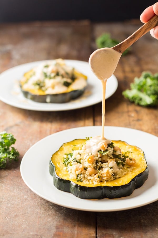 Spoon pouring sauce over Bulgur Stuffed Acorn Squash.