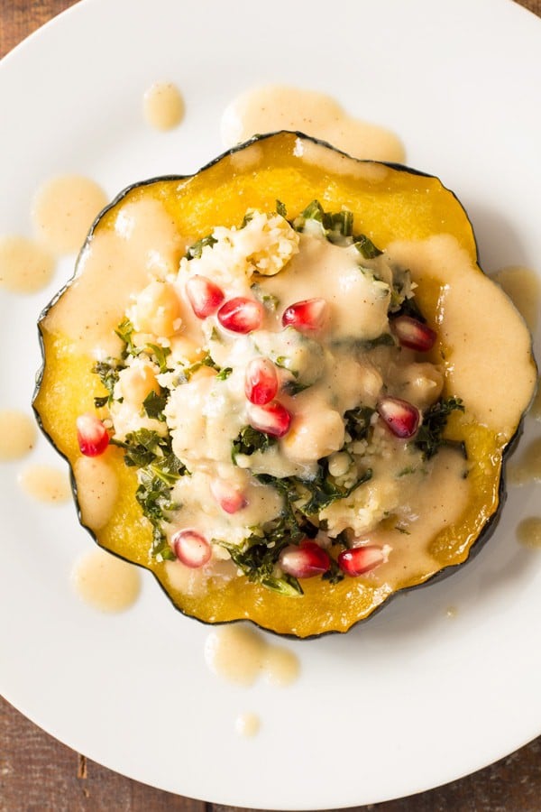 Top view of Bulgur Stuffed Acorn Squash with sauce and pomegranate seeds.