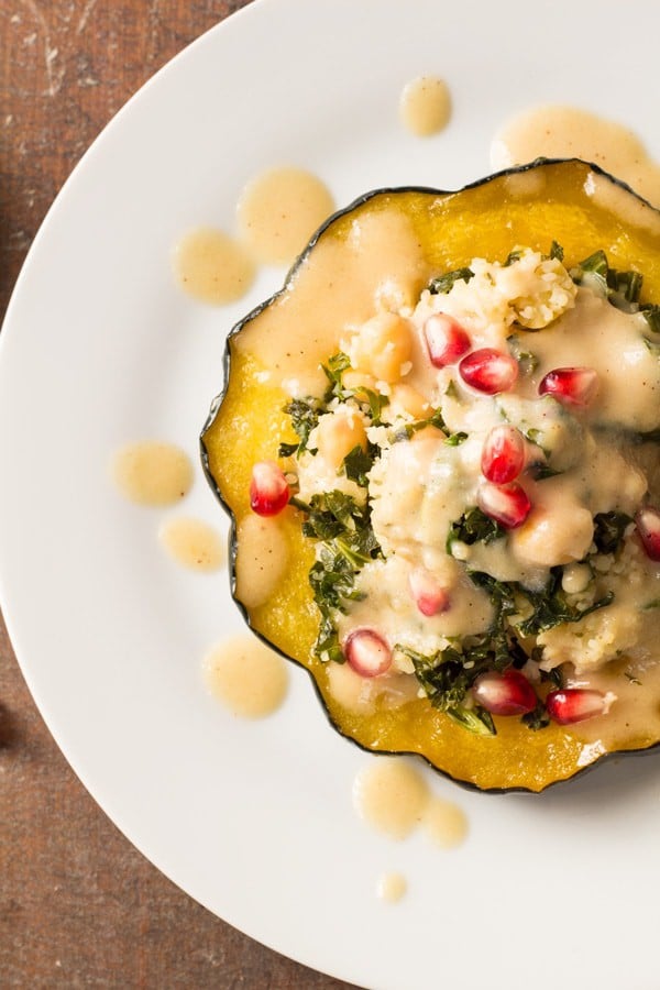 Top view of Bulgur Stuffed Acorn Squash with sauce and pomegranate seeds.