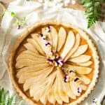 Top view of Simple Pear Tart on a white napkin and some flowers.