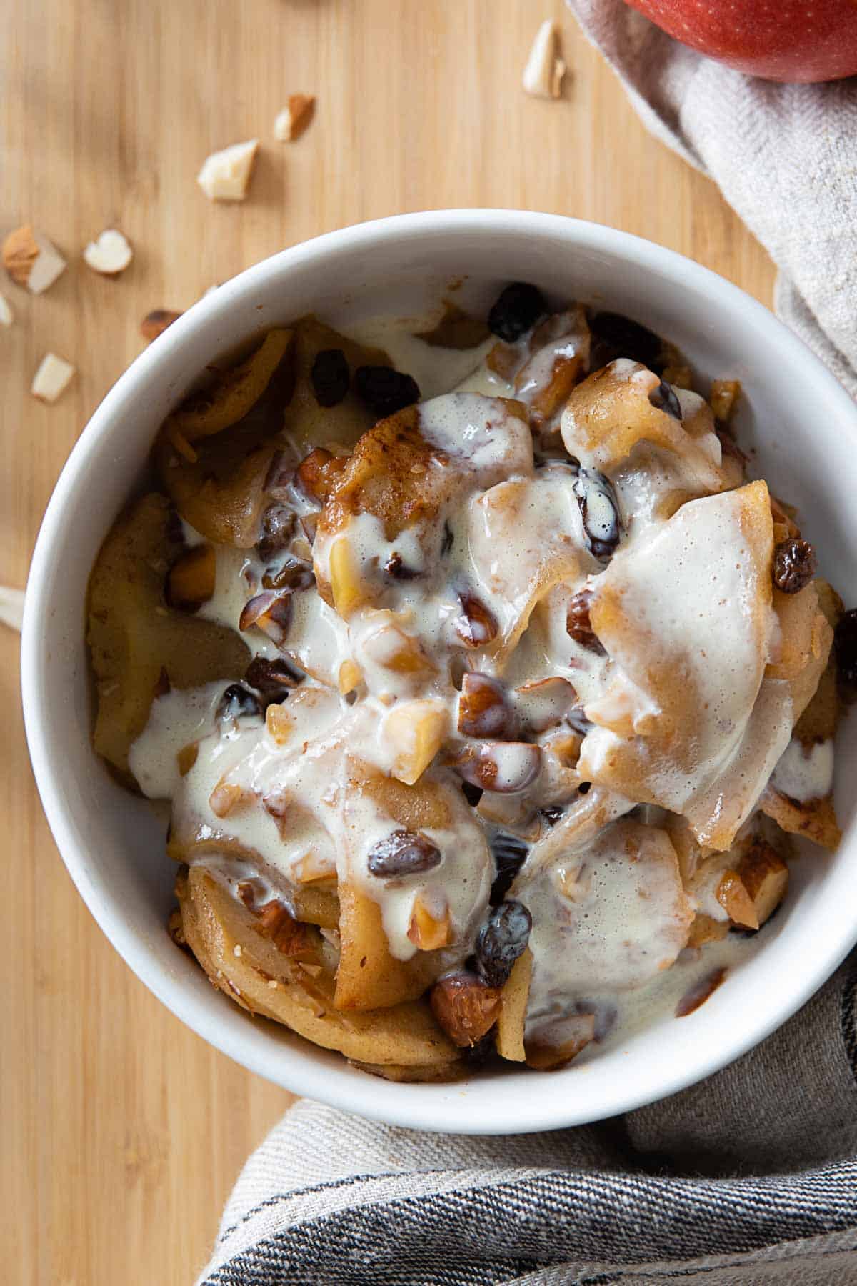 Sliced Baked Apples in a white bowl with custard on top.