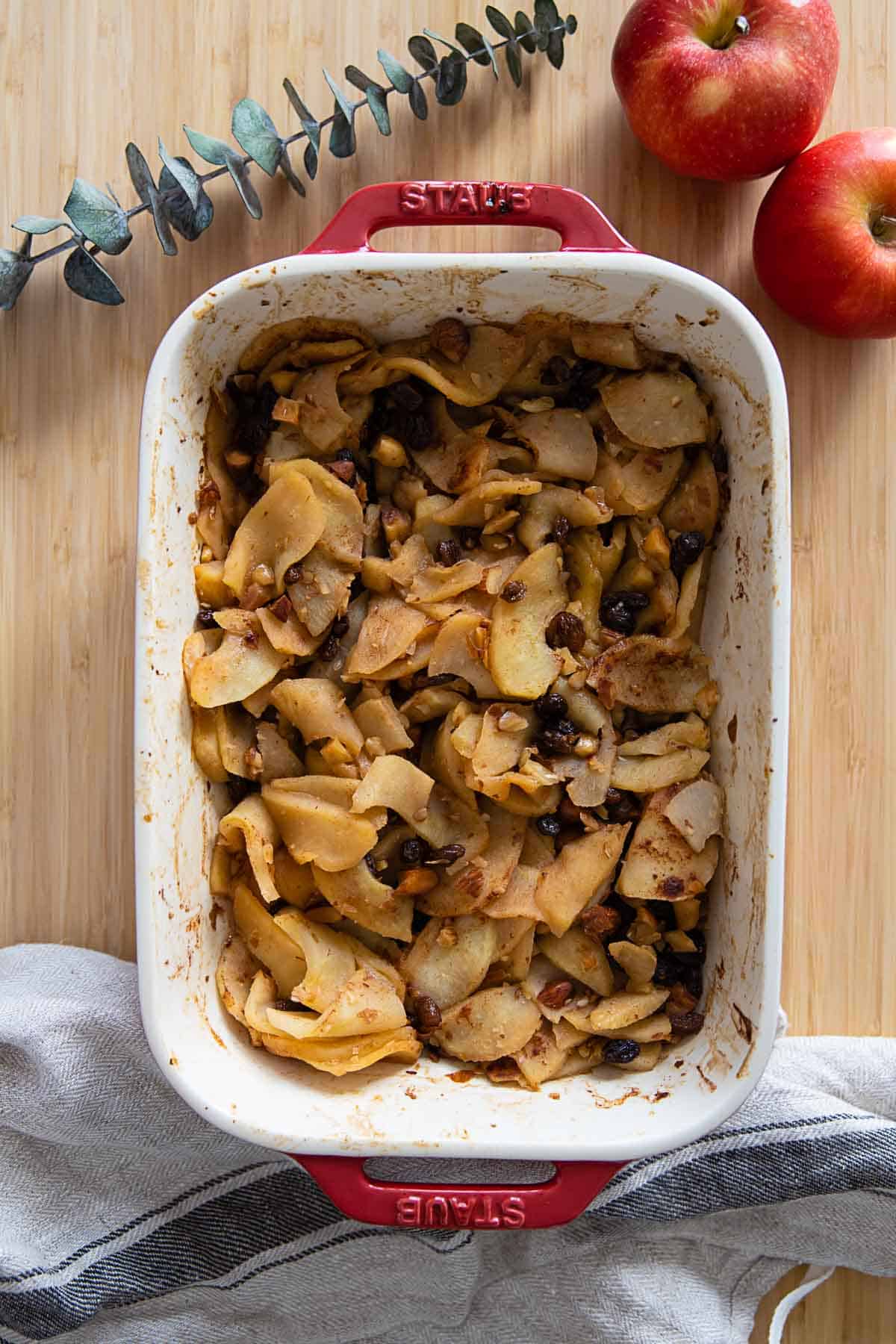 Sliced baked apples in a red baking dish.