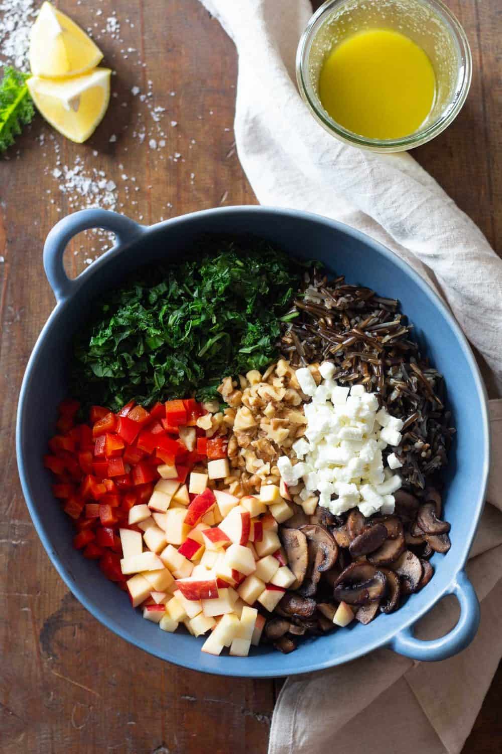 Unmixed wild rice salad ingredients in a blue salad bowl.