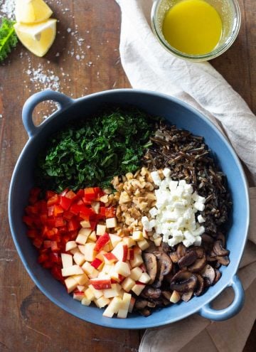 Unmixed wild rice salad ingredients in a blue salad bowl.