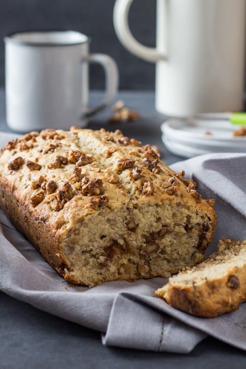 Close up of sliced Banana Bread with Maple Candied Walnuts, and a cup of coffee.