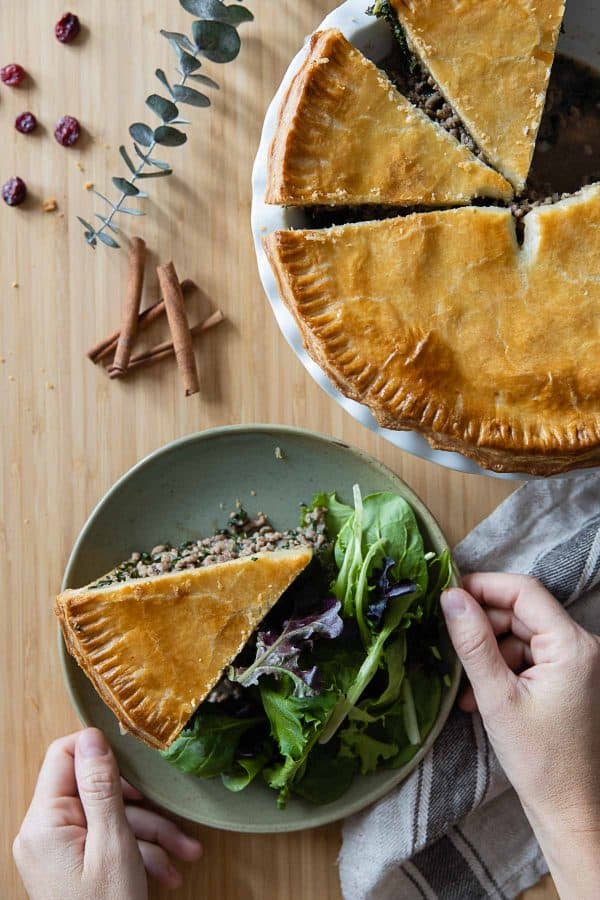 A piece of Tourtière meat pie on a plate with salad on the side.