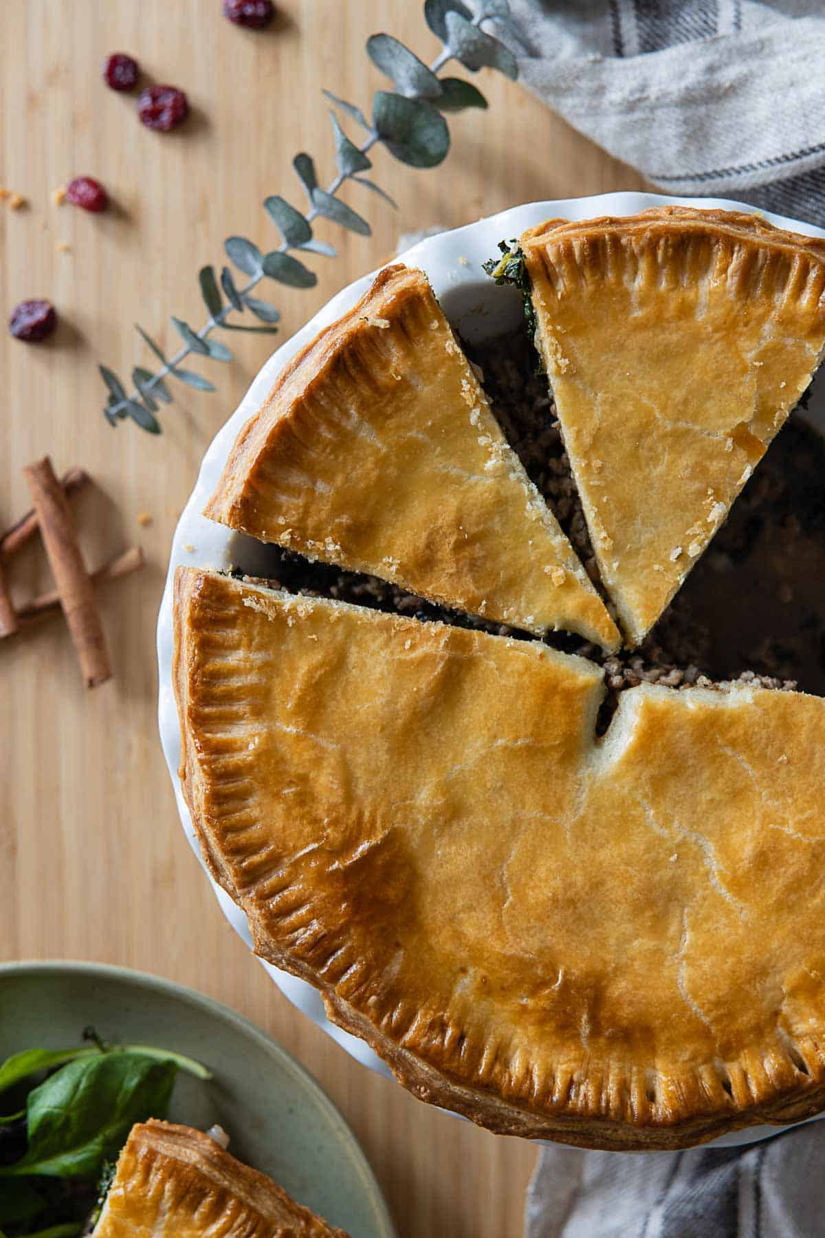 Tourtière meat pie cut up into pieces in baking dish.