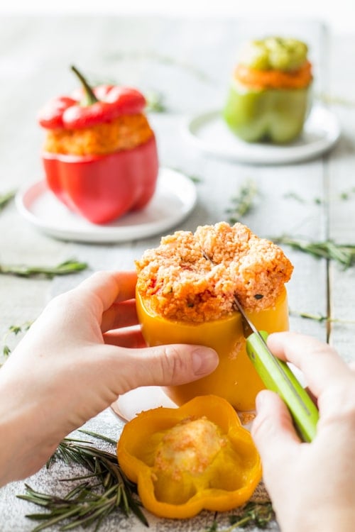 Hand holding a Bulgur Stuffed Bell Pepper and cutting it in half. 
