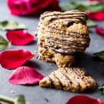 Heart-shaped spelt cookies stacked on the counter with rose petals.