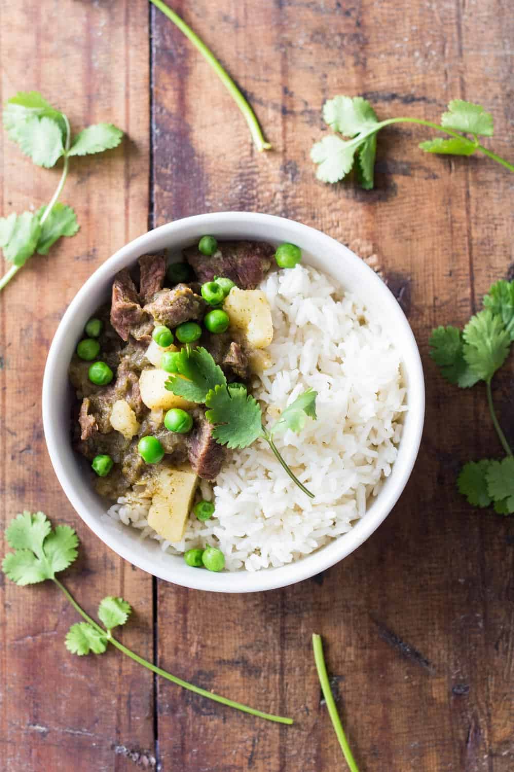 Top view of Peruvian Lamb Stew with rice and peas on a wooden board.