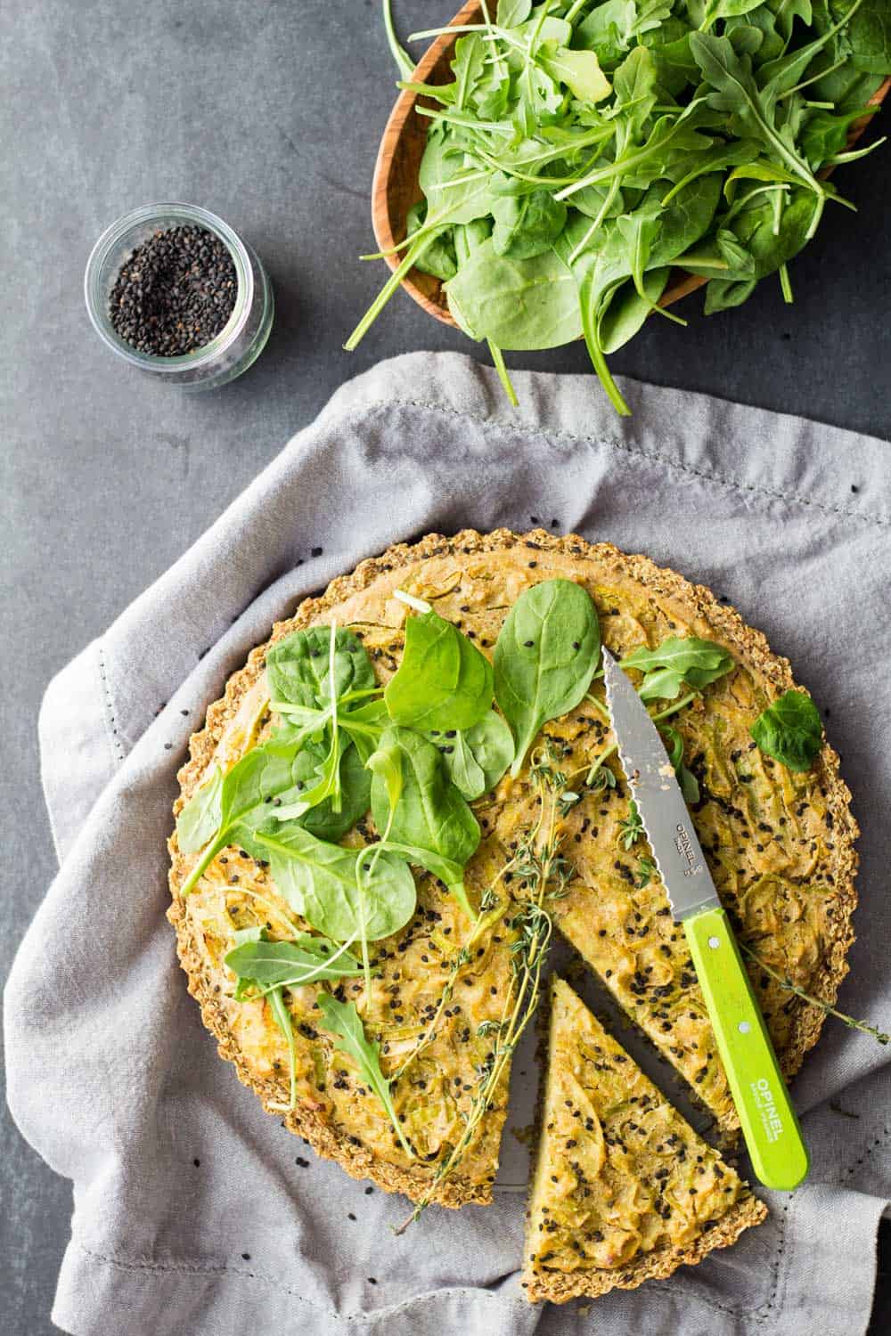 Top view of sliced gluten-free vegan quiche with salad.