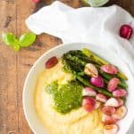 Top view of Creamy Parmesan Polenta with Grilled Vegetables and 5-Minute Basil Pistachio Pesto, an open jar of pesto sauce, and a white napkin.