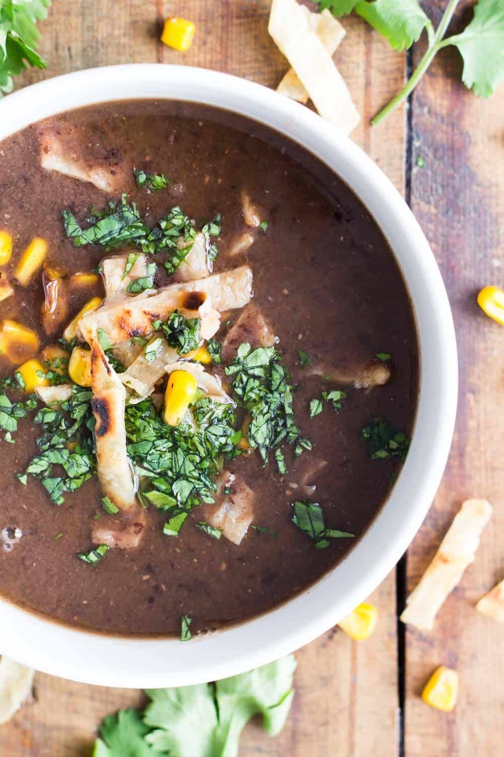 Top view of a bowl of Mexican Black Bean Soup garnished with tortilla strips and cilantro leaves.