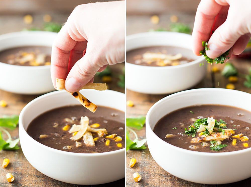 Hands garnishing a bowl of Mexican Black Bean Soup with tortilla strips and cilantro leaves.