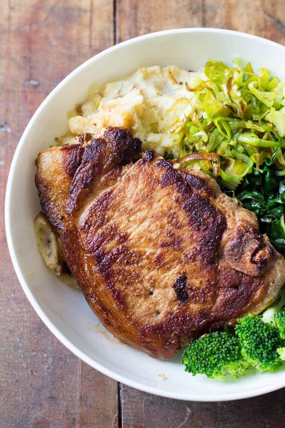 Close up of Perfect Pork Chop with mashed potatoes, celery, chard and broccoli.