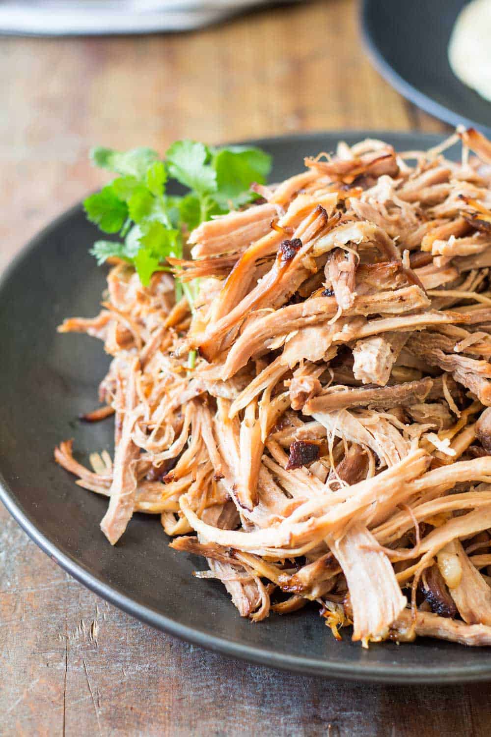 Close up of pulled pork on a black plate to show texture.