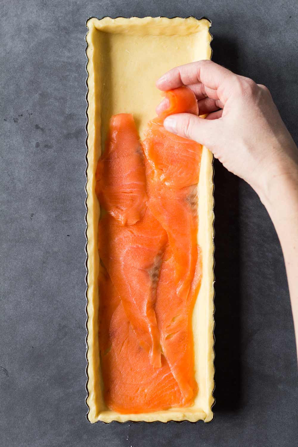 placing slices of smoked salmon into a puff pastry crust