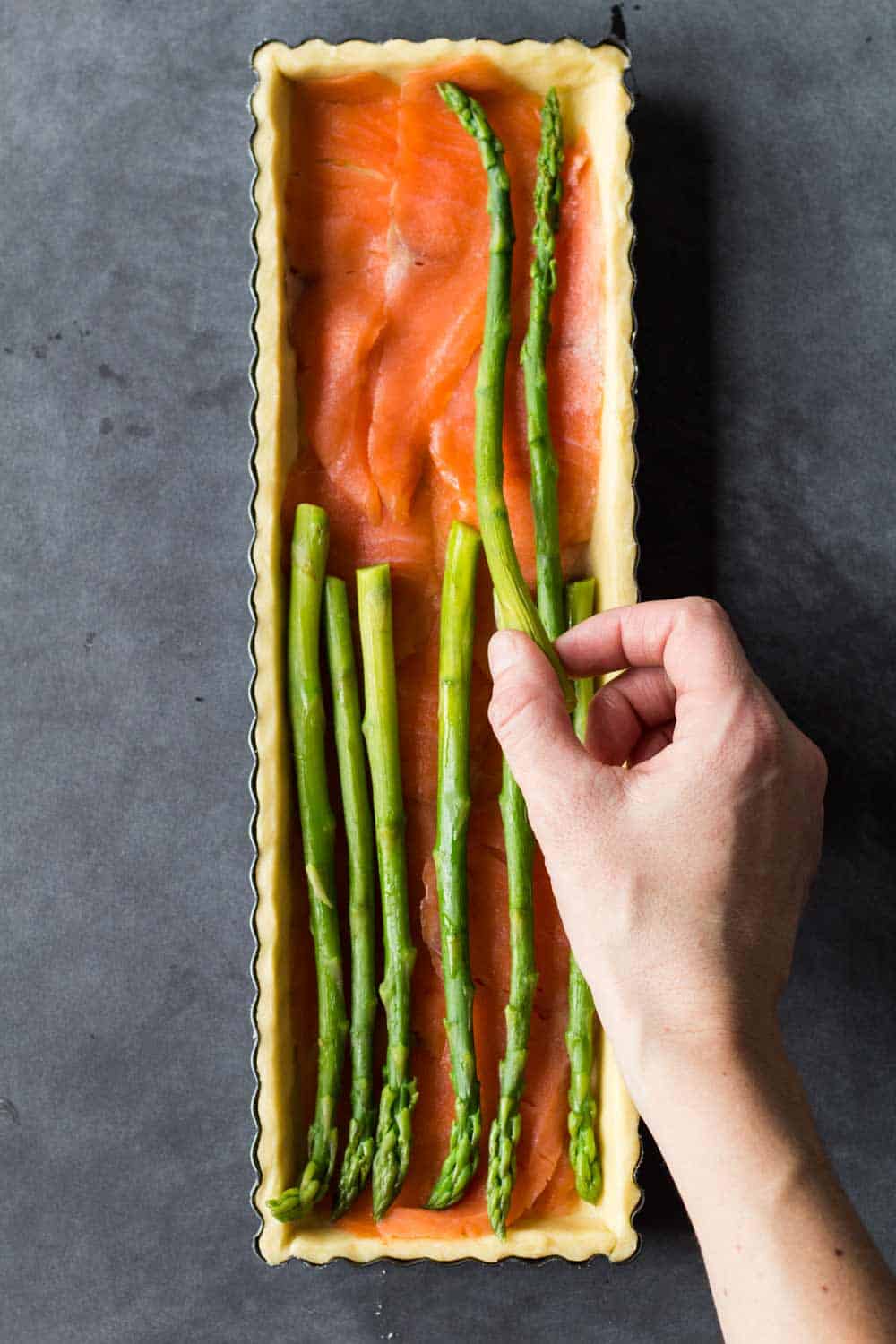 assembling smoked salmon and asparagus quiche