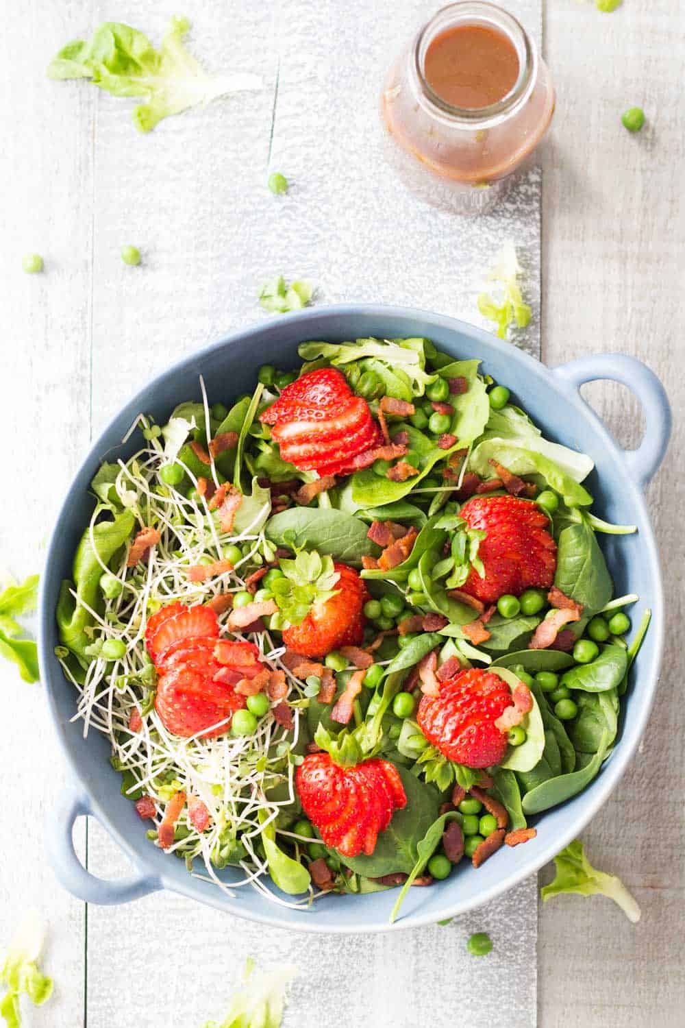 Top view of Strawberry Bacon Spring Salad and a jar of Maple Mustard Balsamic Dressing.