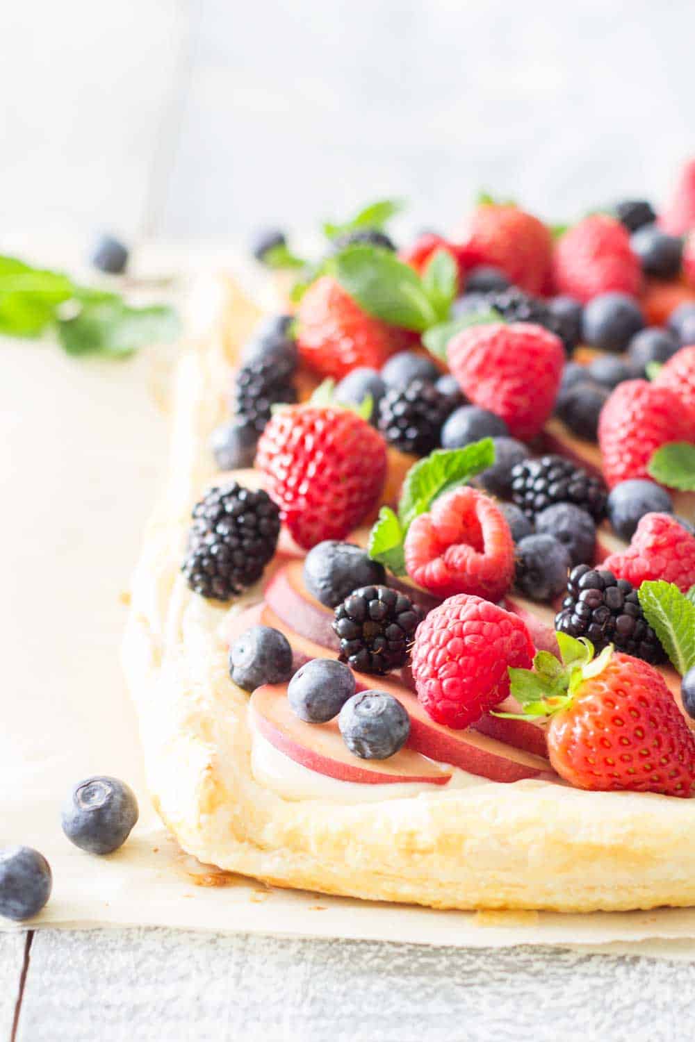 Close up of Summer Fruit Tart with peach slices, blueberries, blackberries, raspberries, and strawberries, to show texture.