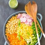 Top view of Romaine Lettuce Salad with a jar of Herb Vinaigrette, and a wooden salad fork and spoon.