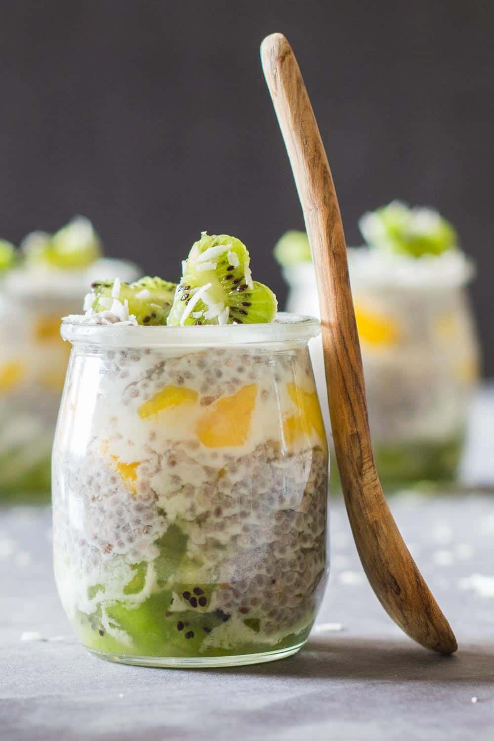 Close up of jar of Tropical Chia Pudding with a wooden spoon.