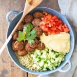 Top view of Vegan Quinoa Falafel Bowl garnished with fresh parsley, and a wooden spoon.