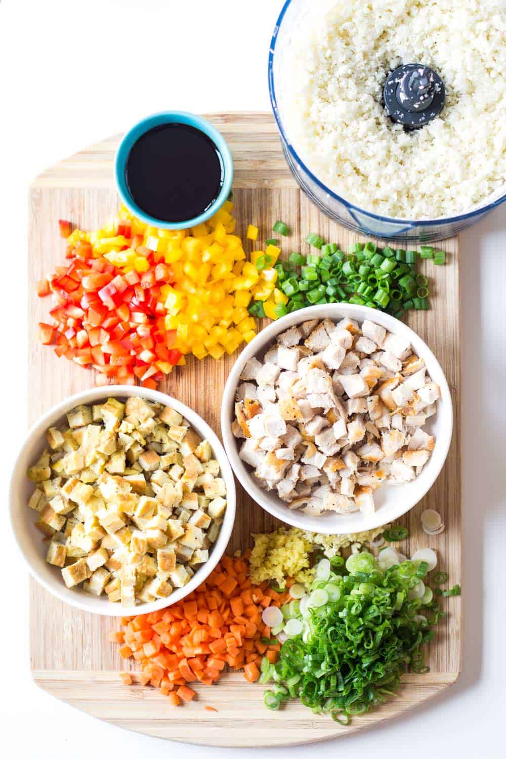 Fresh chopped ingredients for Cauliflower Fried Rice laid out on a chopping board.
