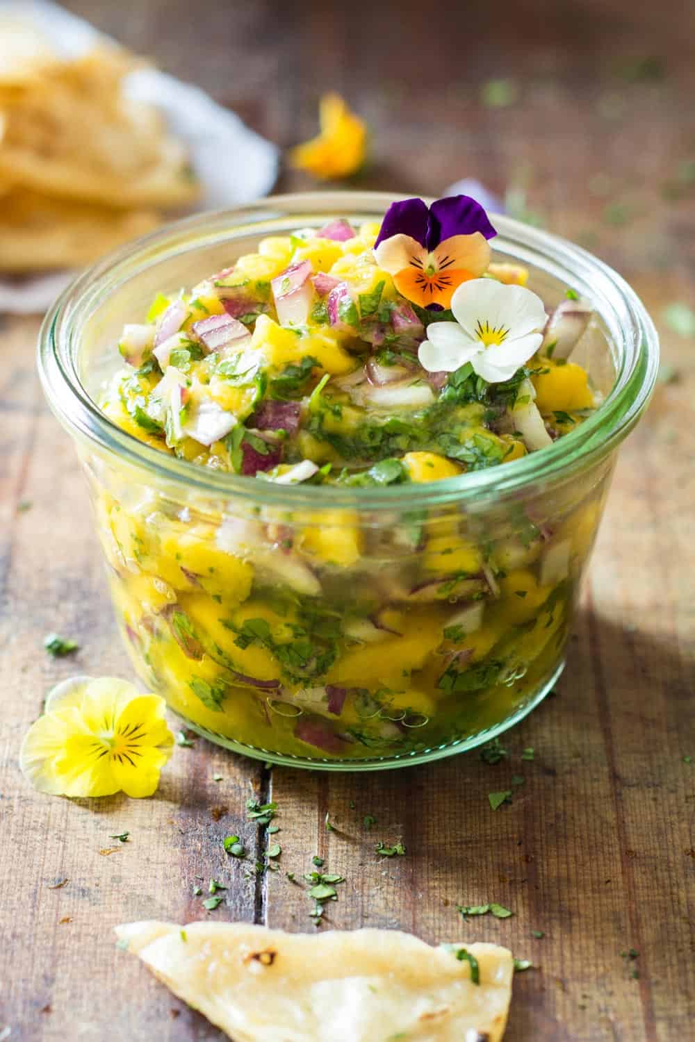 Jar of Mango Salsa topped with fresh flowers.