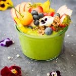 Green Smoothie Bowl topped with fresh fruit and fresh flowers.