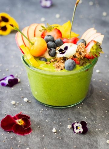Green Smoothie Bowl topped with fresh fruit and fresh flowers.