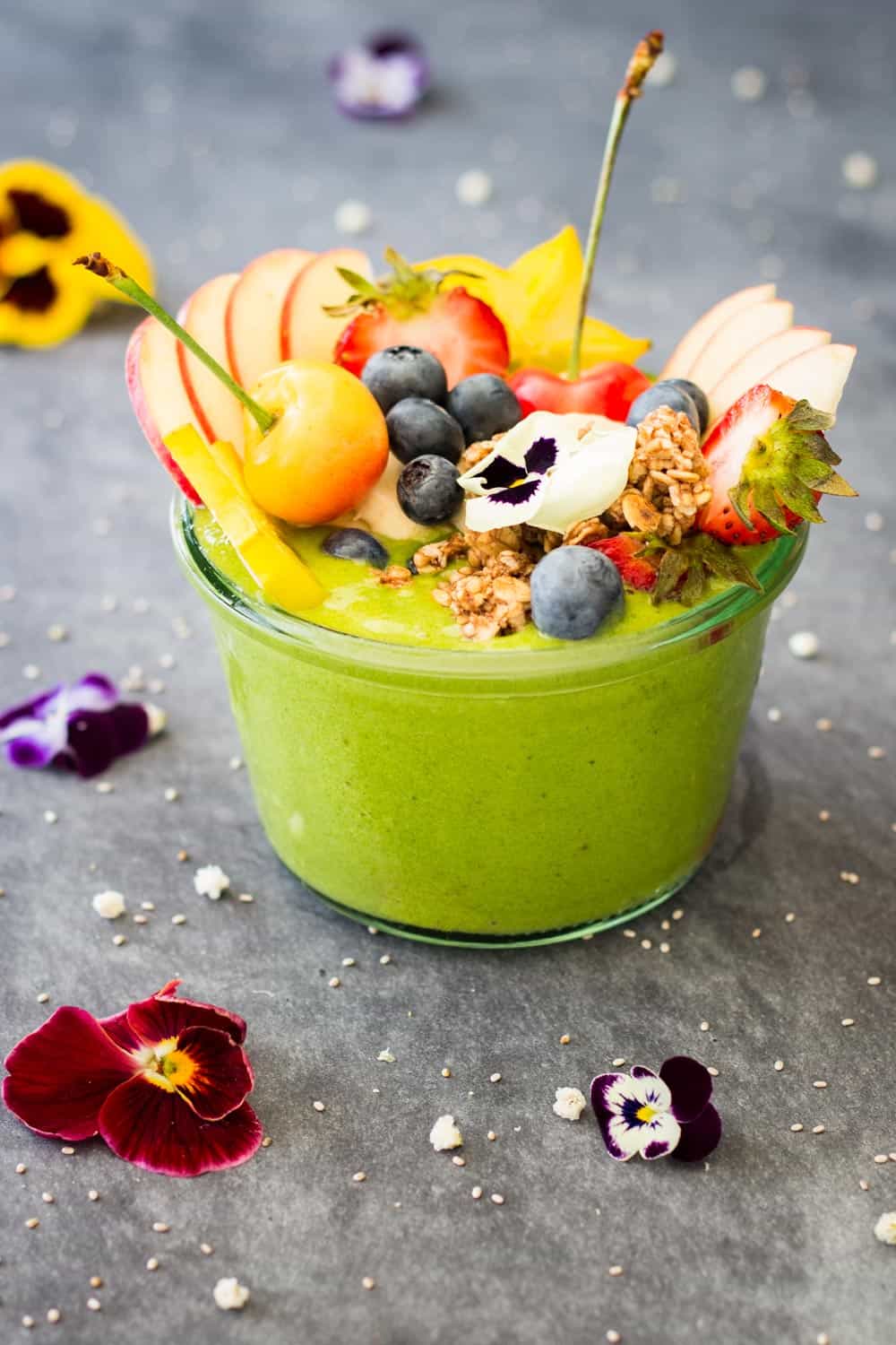 Green Smoothie Bowl topped with fresh fruit and fresh flowers.