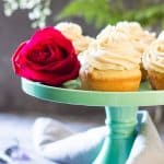 Moist Vanilla Cupcakes on a green cake stand with a rose.
