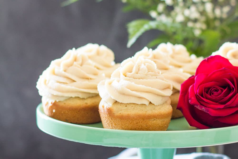 Moist Vanilla Cupcakes on a green cake stand with a rose.